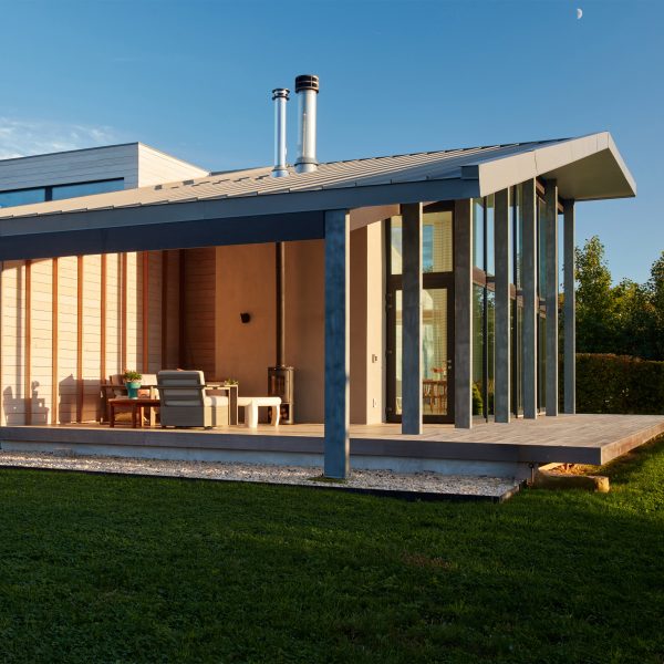 Exterior of a large porch of a house with cedar-clad walls and pitched roof