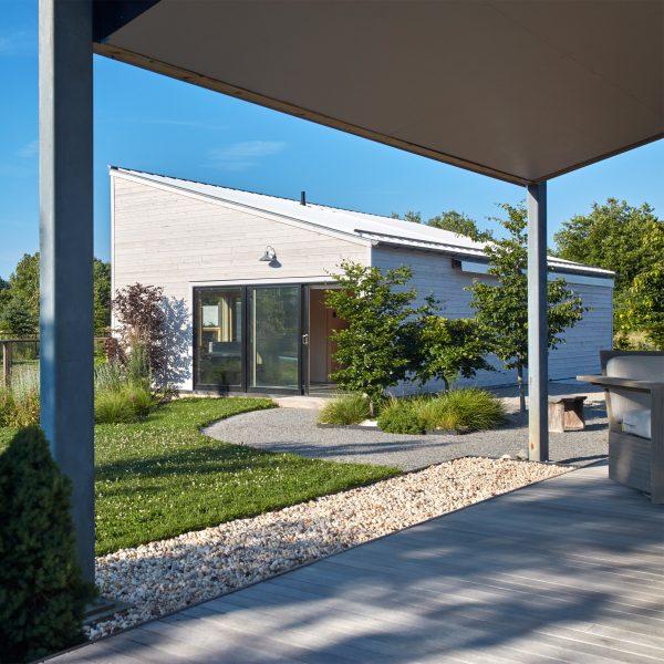 Outdoor porch area overlooking a mono-pitched structure across grassy landscaping