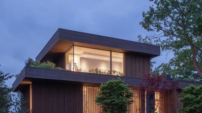 Exterior of a two-storey timber-clad lake house with front lawn by Worrell Yeung