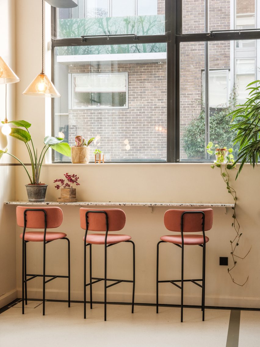 Pink bar stools by a white wall with large windows in metal frames