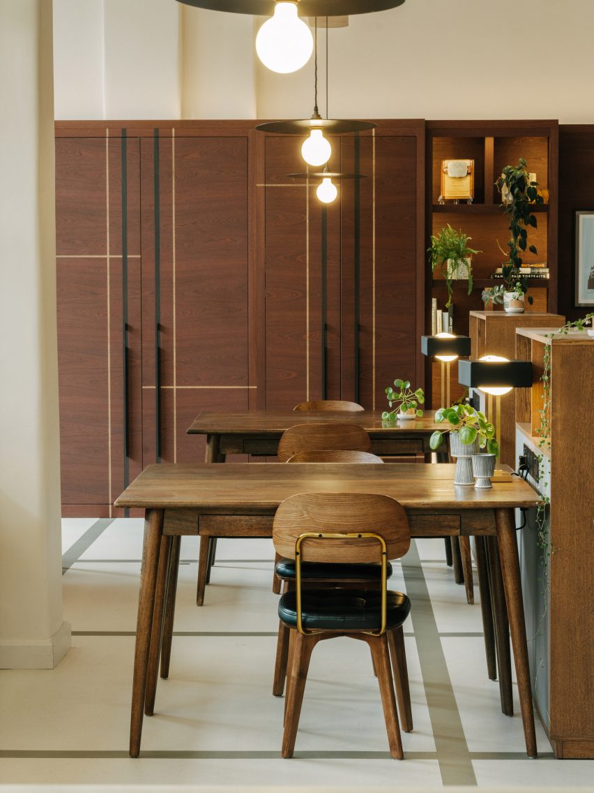 Flexible office space with white walls and floors, decorated with dark wood midcentury furniture