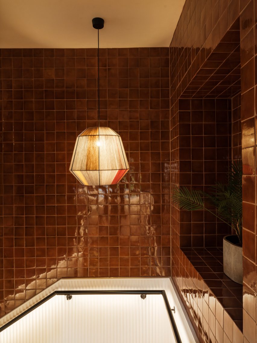 Staircase with square brown tile walls and glass pendant light