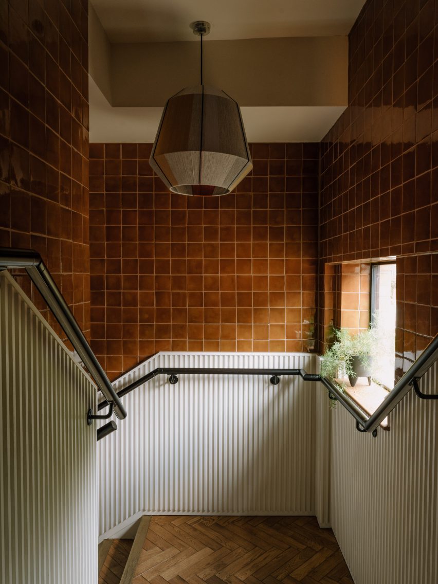Staircase with brown tile walls, white panelling and glass pendant lamp