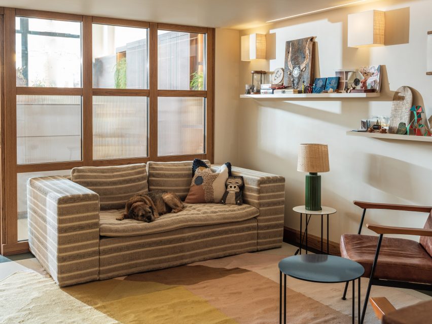 Lounge space with brown and cream striped sofa, side tables and glass partition wall
