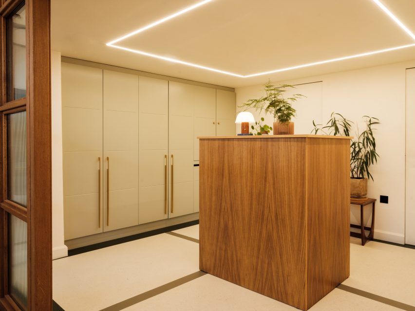 White room with recessed strip lighting, built-in wardrobes and wood table