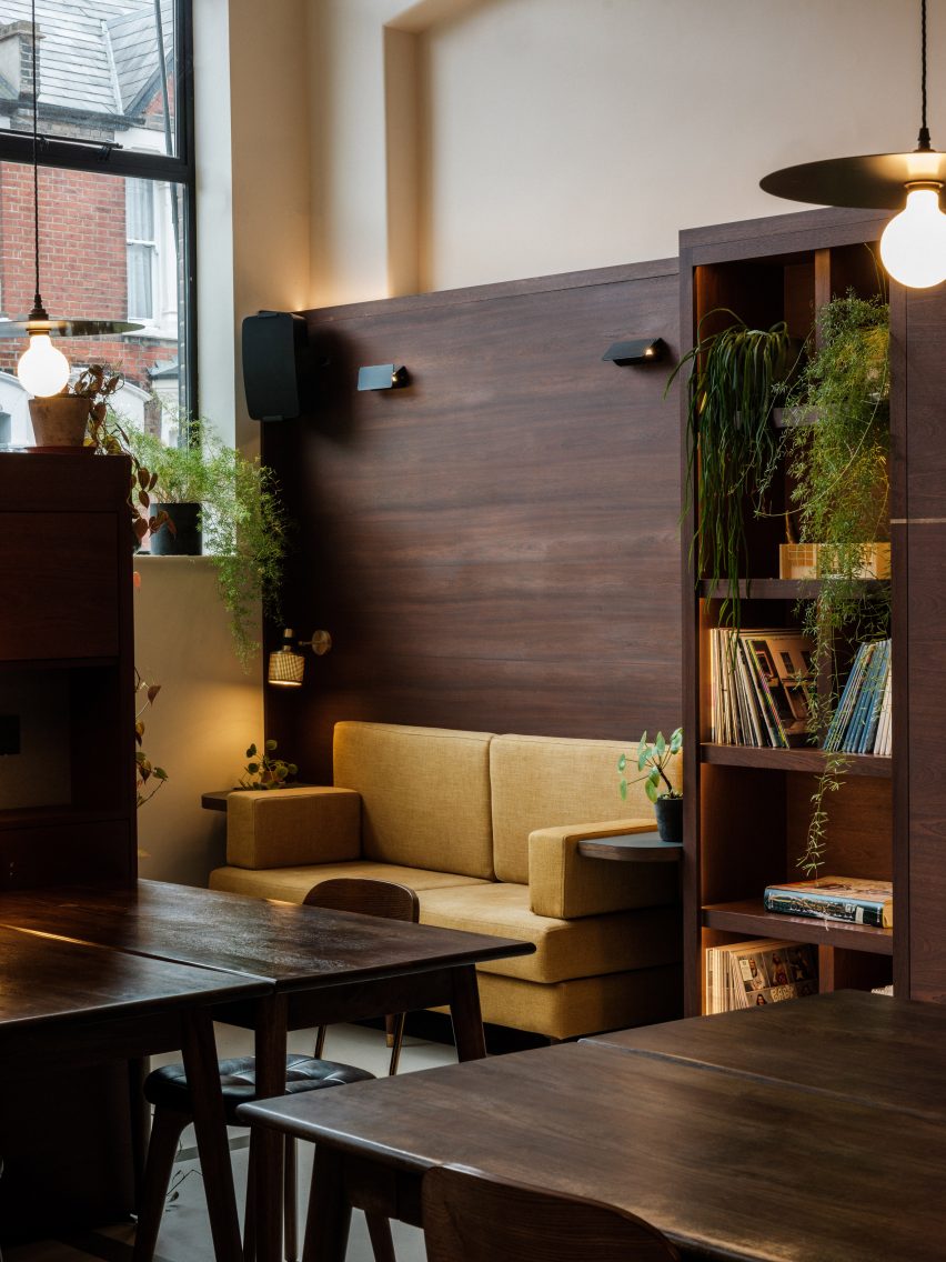 Office space with dark wood desks, wall panelling and a yellow sofa