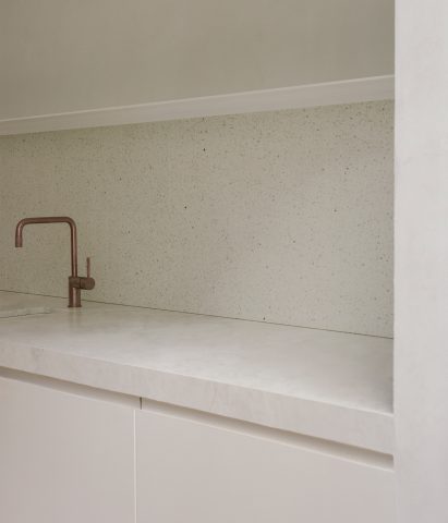 White kitchen with stone countertop and a brass tap