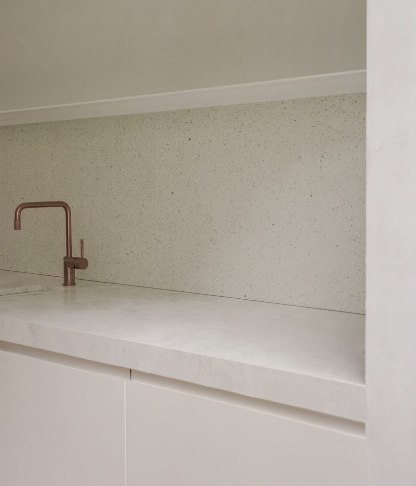 White kitchen with stone countertop and a brass tap