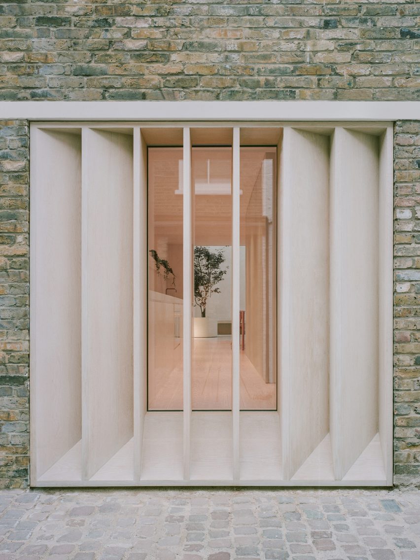 Bespoke timber louvres on a brick home in front of a large window looking into a white kitchen