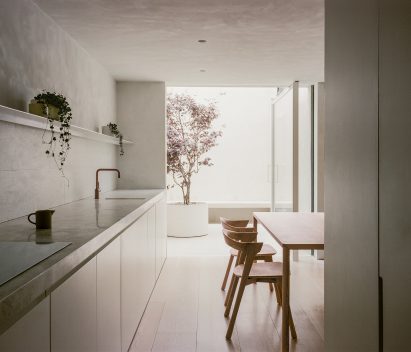 Open plan kitchen and dining space with the kitchen counter on one wall and an outdoor courtyard at the end