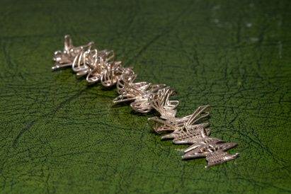 Photo of an abstract 3D-printed object made of interwoven silver alloy