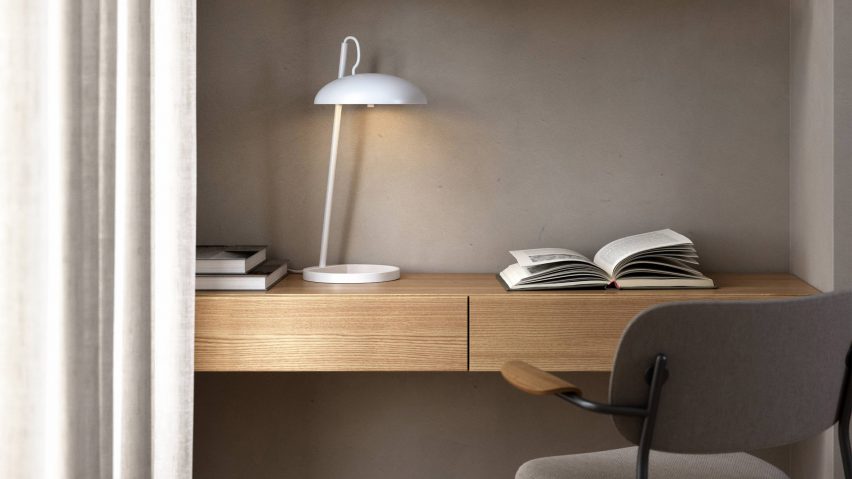 White table lamp on a wood desk fixed to a mauve wall