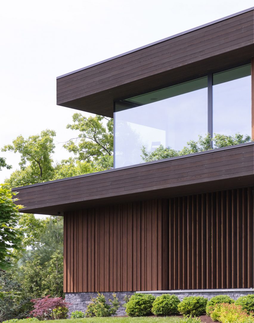 Timber-clad house with cantilevered roof planes topped with greenery