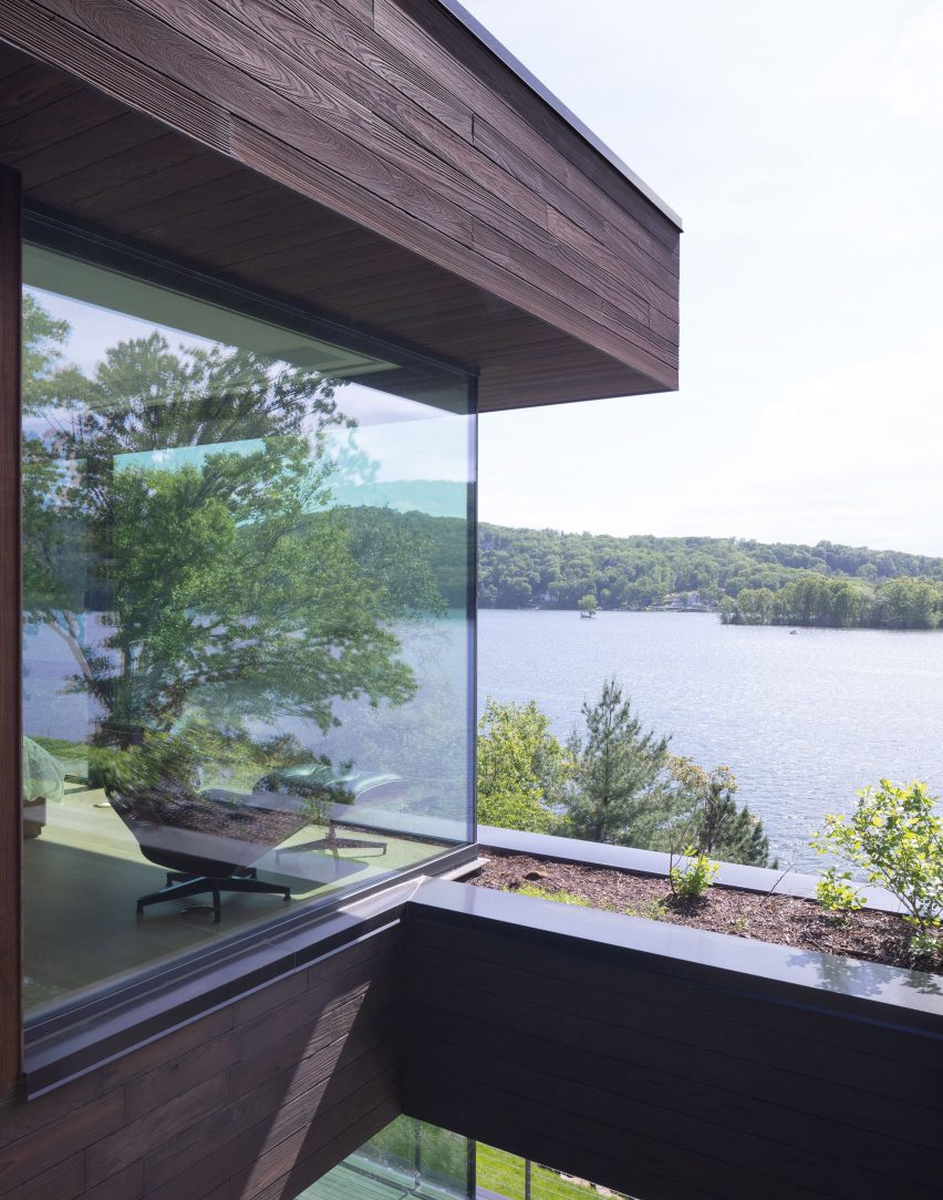 Exterior view of a chair at a corner window overlooking a lake