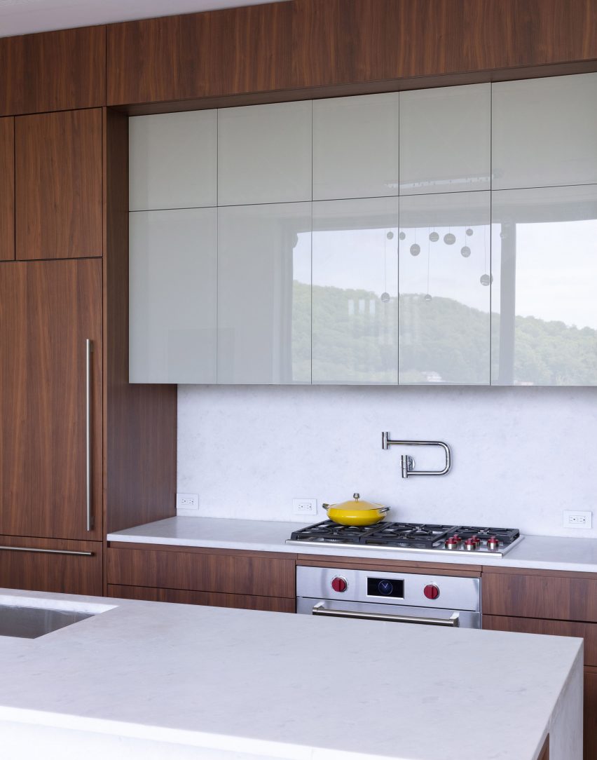 A kitchen with walnut and white glossy kitchen cabinets with white countertops