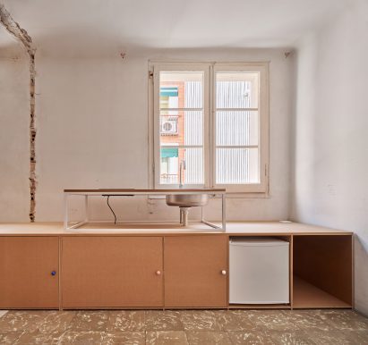 Low-slung wooden cabinets within the kitchen of apartment with white walls