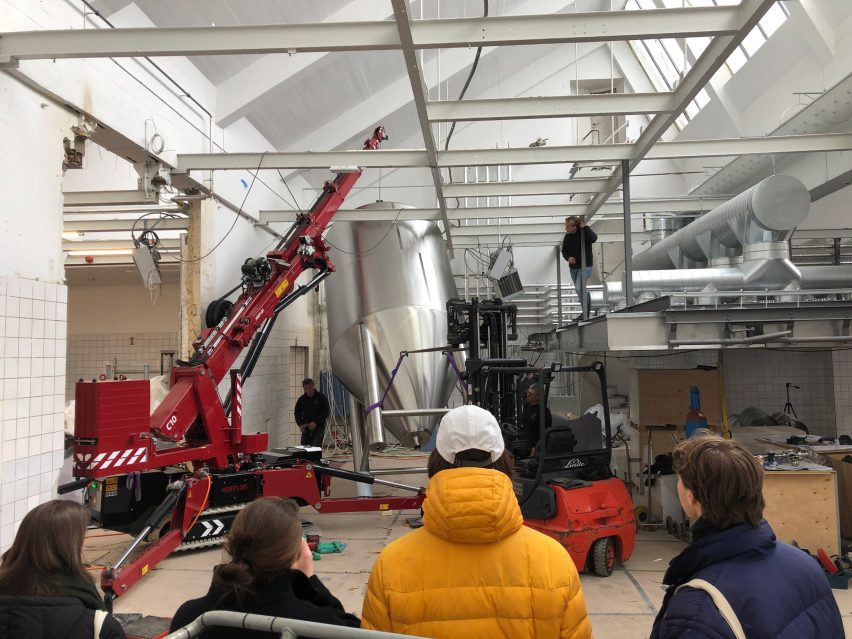 Construction workers moving the fermentation tanks into the space
