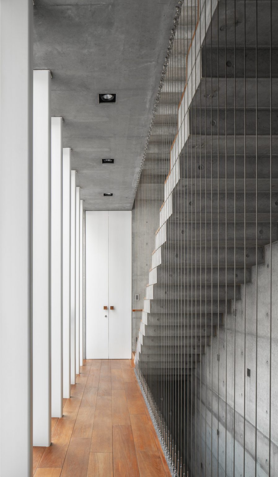 Interior corridor with wooden flooring and a concrete staircase