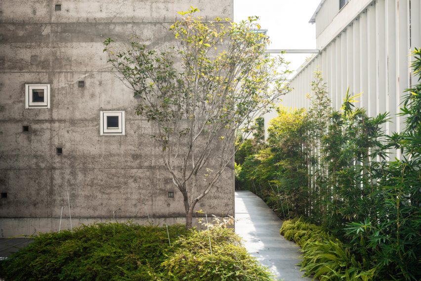 Concrete exterior wall of a home with a side path and green planting