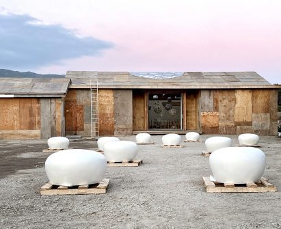 A plywood building on a construction site with white domes in front