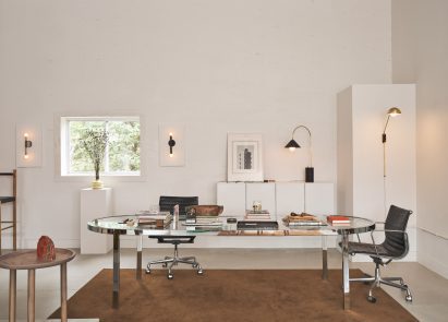 Glass-topped metal desk positioned on a brown rug
