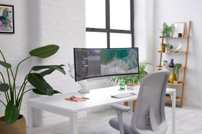 Wide curved screen held up by white monitor arm