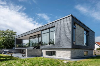 Slate-clad rectangular building with large windows on grass