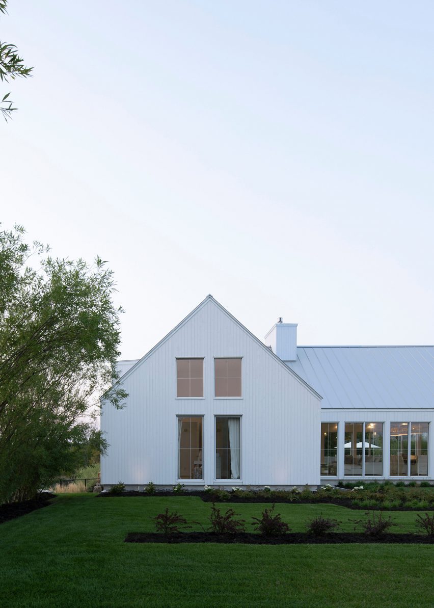 A white house with a gable end with windows in garden
