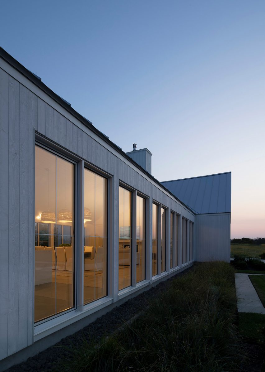 A one-storey structure with large windows and white timber cladding