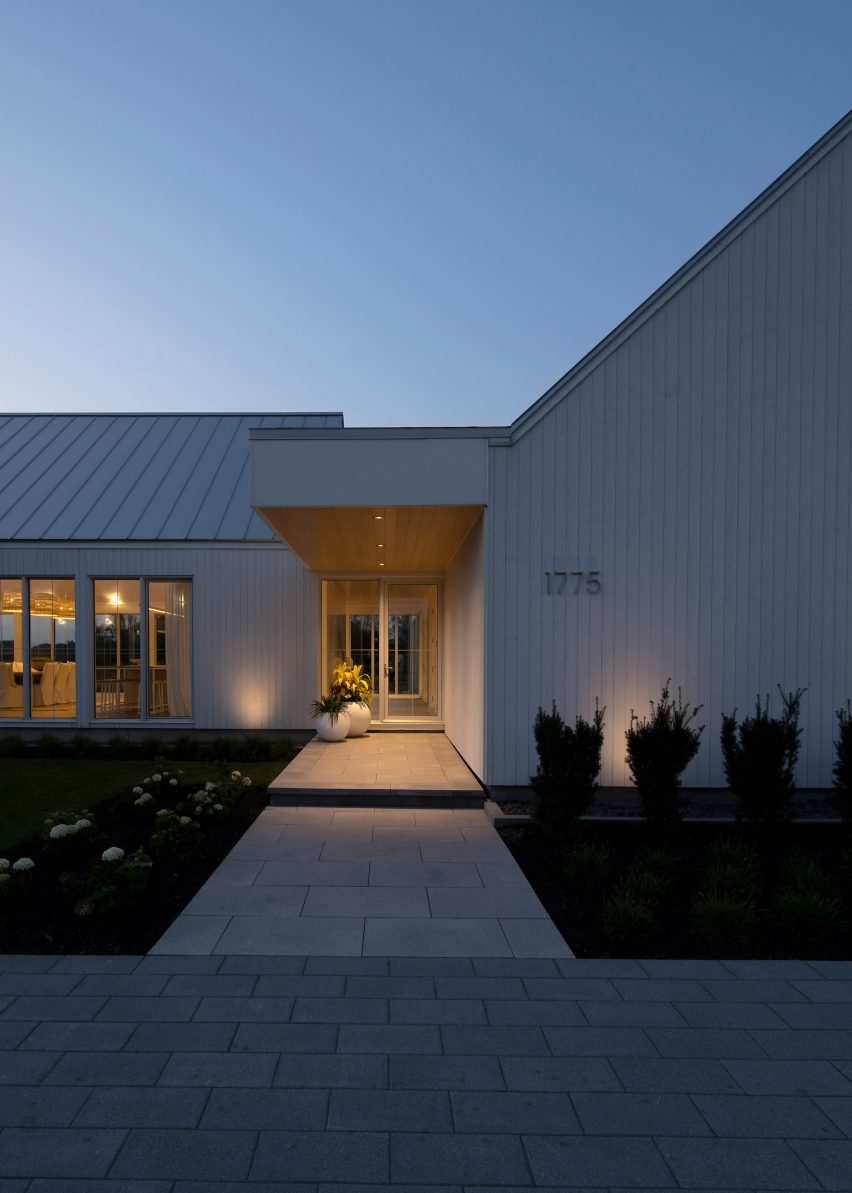 Entrance to a white timber-clad home with a planted from garden