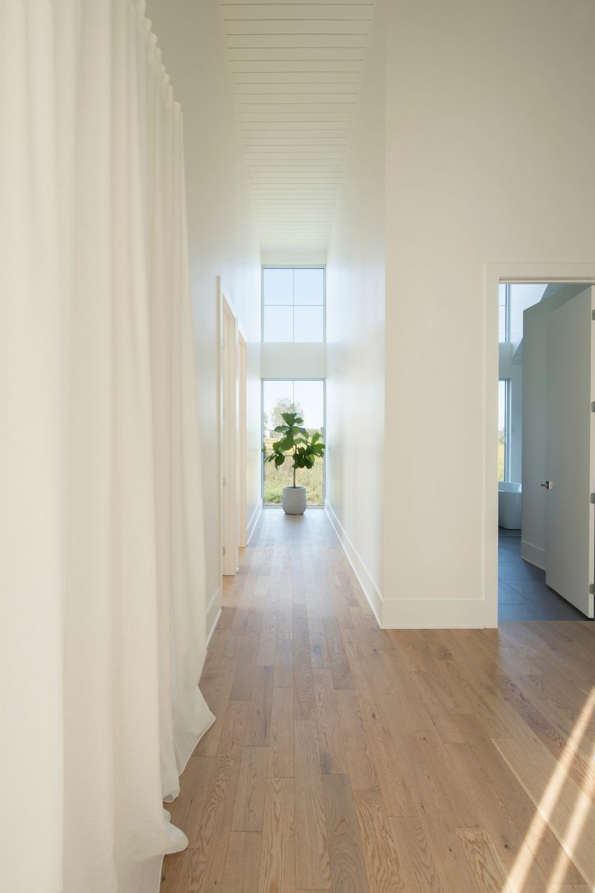 A hallway with timber floors, white walls and white curtains