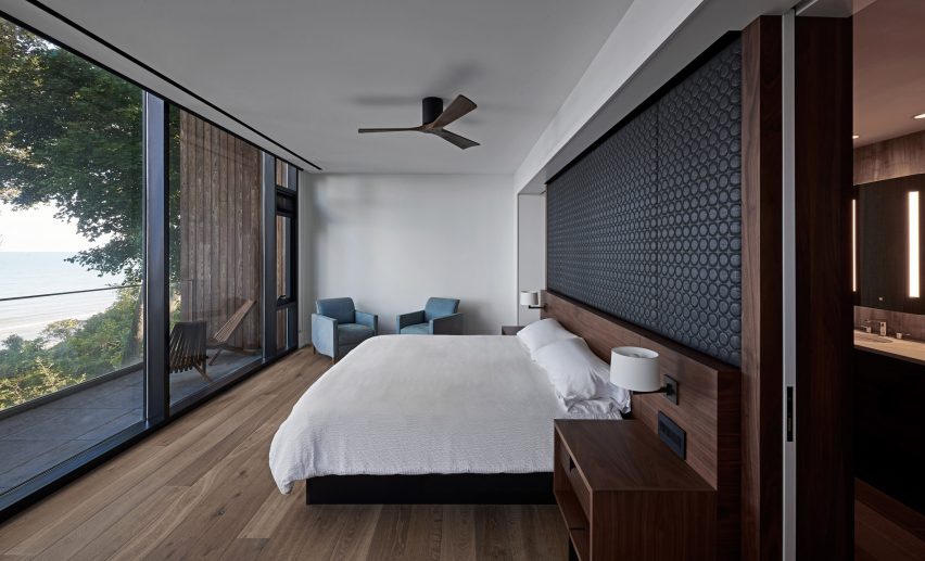 A bedroom with oak flooring, white walls, a white bed with a black headboard