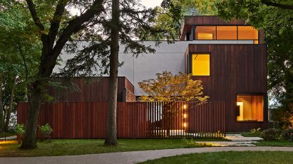 Exterior of a home with rectangular forms clad in concrete and timber with a grass front garden