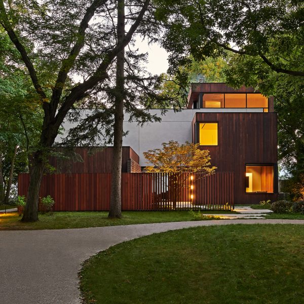Exterior of a home with rectangular forms clad in concrete and timber with a grass front garden