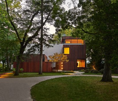 Exterior of a home with rectangular forms clad in concrete and timber with a grass front garden