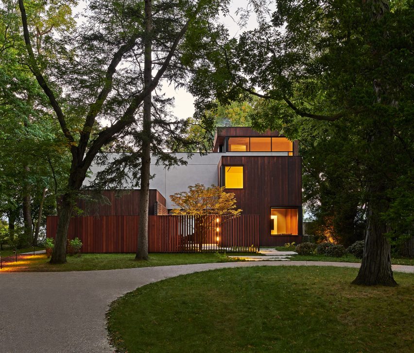 Exterior of a home with rectangular forms clad in concrete and timber with a grass front garden