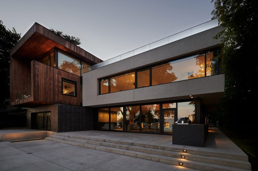 Timber decking outside a three-storey home with timber and concrete cladding and large windows