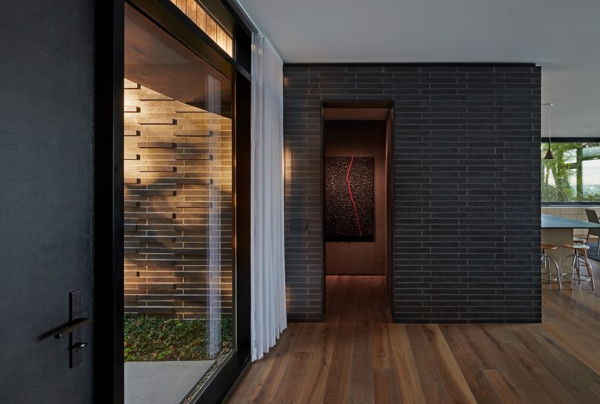 Interior room with oak flooring, black brick walls and floor-to-ceiling window