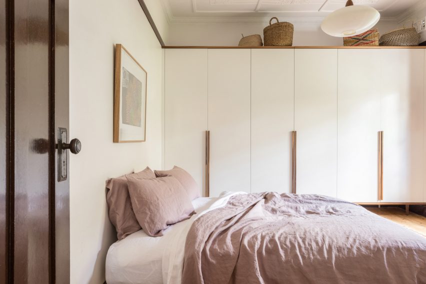 Bedroom with white cupboards and a bed with pink bedding