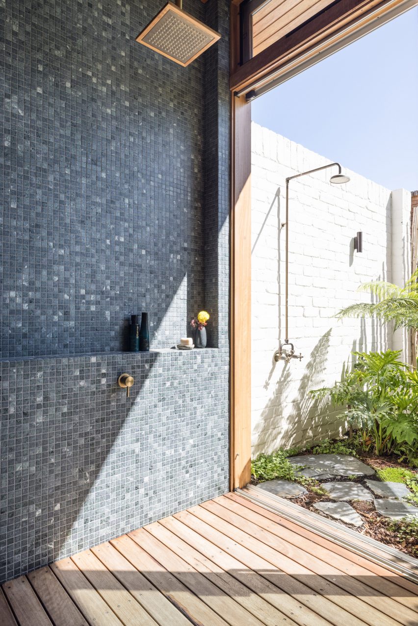 Bathroom with dark mosaic wall tiles and and outdoor shower
