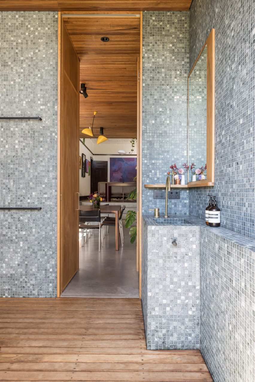 Bathroom with dark mosaic wall tiles, wood deck flooring and niche