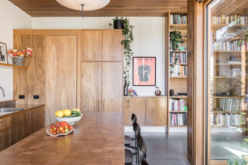 Open-plan kitchen and dining room with concrete flooring, wood kitchen island with seating and wood storage cupboards