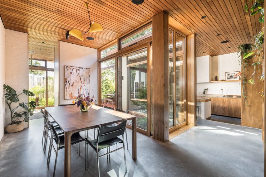 Open-plan kitchen and dining room with wood ceiling and table
