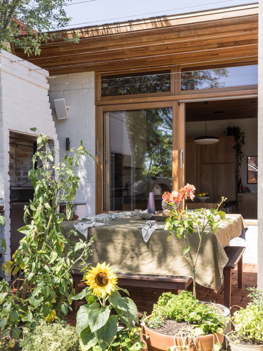 Outdoor dining space with white walls and leafy planting