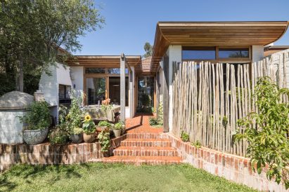 Rear garden of a bungalow with brick steps leading to a patio and home extension