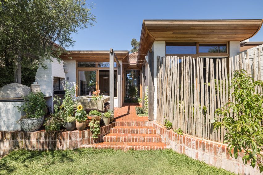 Rear garden of a bungalow with brick steps leading to a patio and home extension