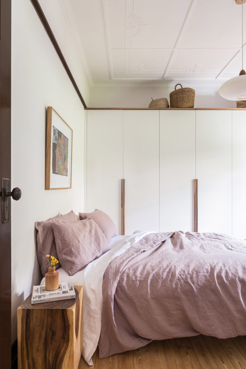 Bedroom with white walls, wood flooring and double bed with pink bedding