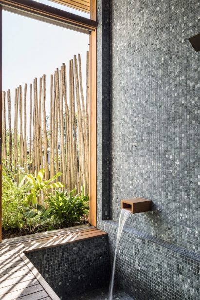 Bathroom with sunken bath, blue tiled walls and a window overlooking a garden