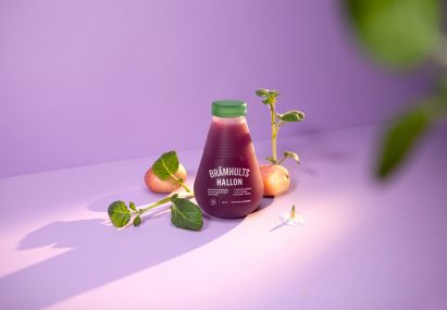 Clear bottle with green cap arranged next to sprouting potatoes