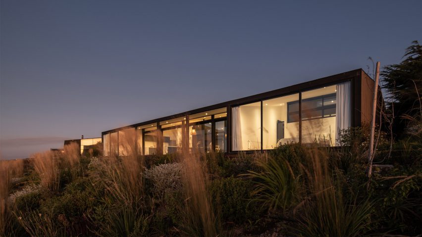 Exterior of a one-storey open-plan home with glazed walls on a hillside